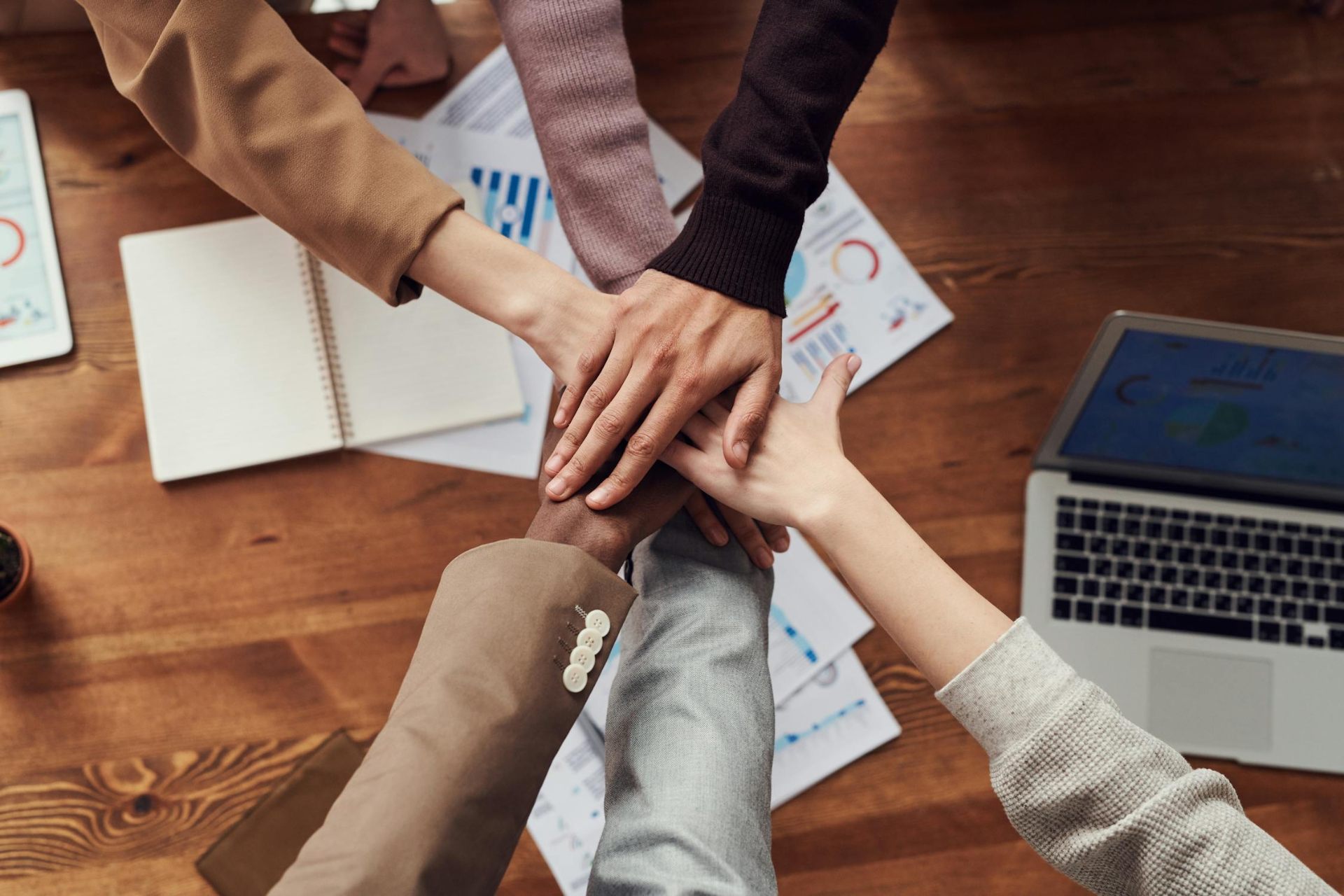 Team building hands together over a workspace